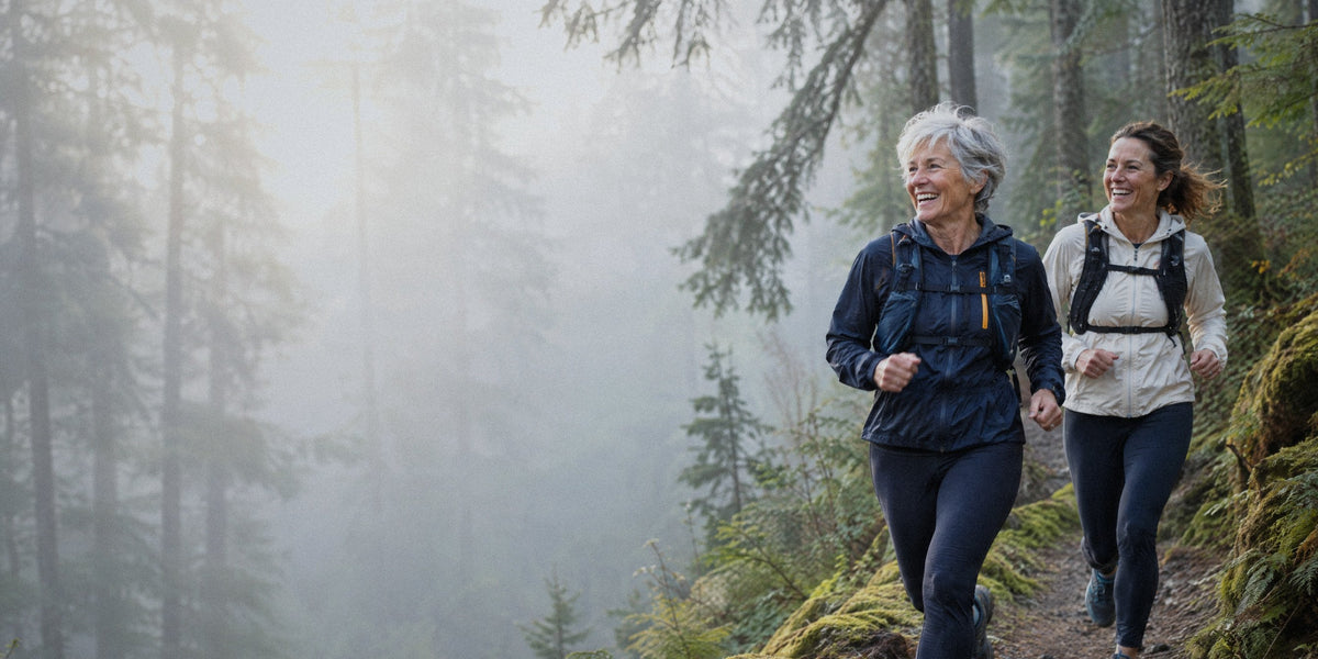A woman in her seventies and her daughter in her forties running a misty Oregon forest trail at sunrise