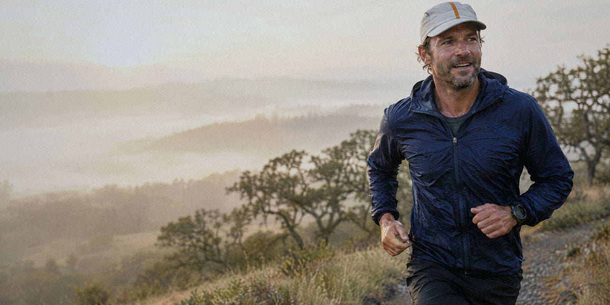 A man in his forties running a misty Oregon oak-savanna trail at sunrise