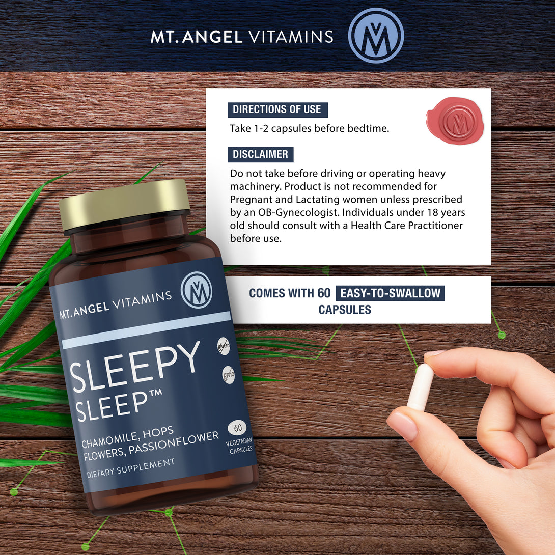 Blue bottle of Mt. Angel Vitamins Sleepy Sleep on a wood background, with the directions for use in a white box next to the product. A woman's hand is shown holding one of the white Mt. Angel Vitamins Sleepy Sleep capsules. The Mt. Angel Vitamins logo is on the top.